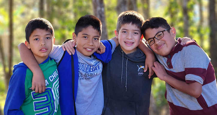 Four young boys including Joaquin on the right are pictured together outside at Valley of the Angels in Guatemala. They are clean, bright, and smiling with their arms around each other.]