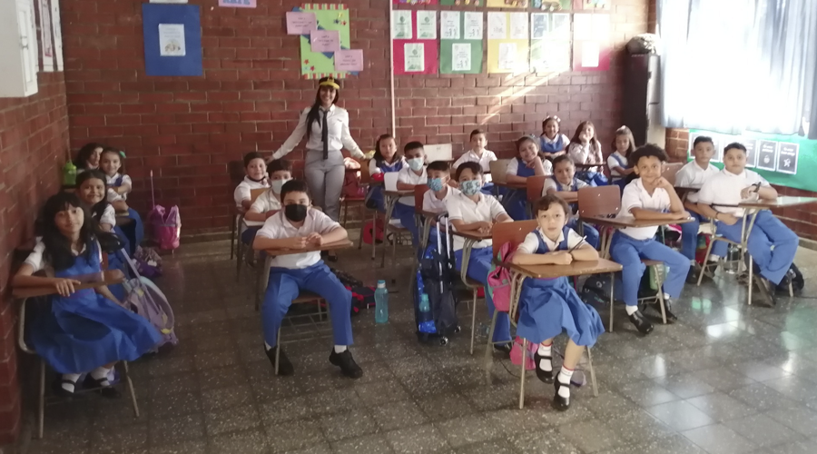 A photograph of young students sitting at desks in a classroom at our AGAPE mission school in El Salvador.